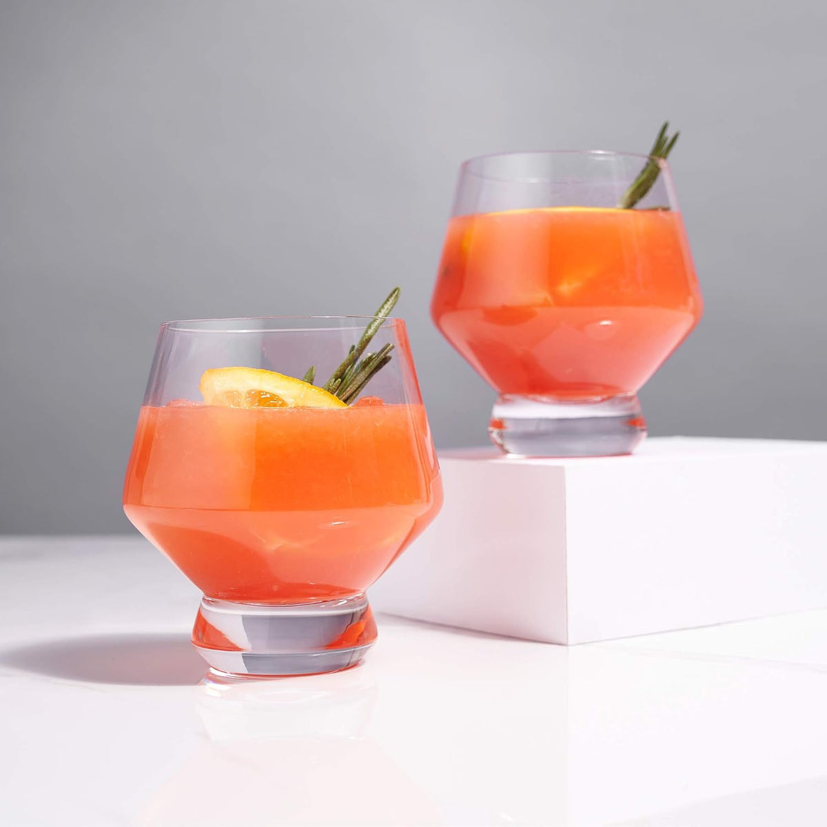 Viski Raye punch cups with orange cocktails on a white surface