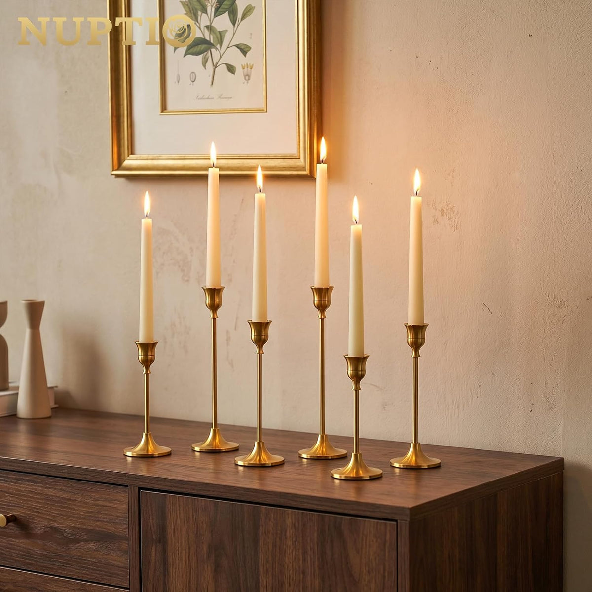Gold candle holders with lit candles on a wooden console