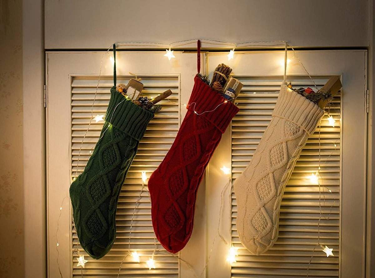 Three knit stockings hanging with string lights