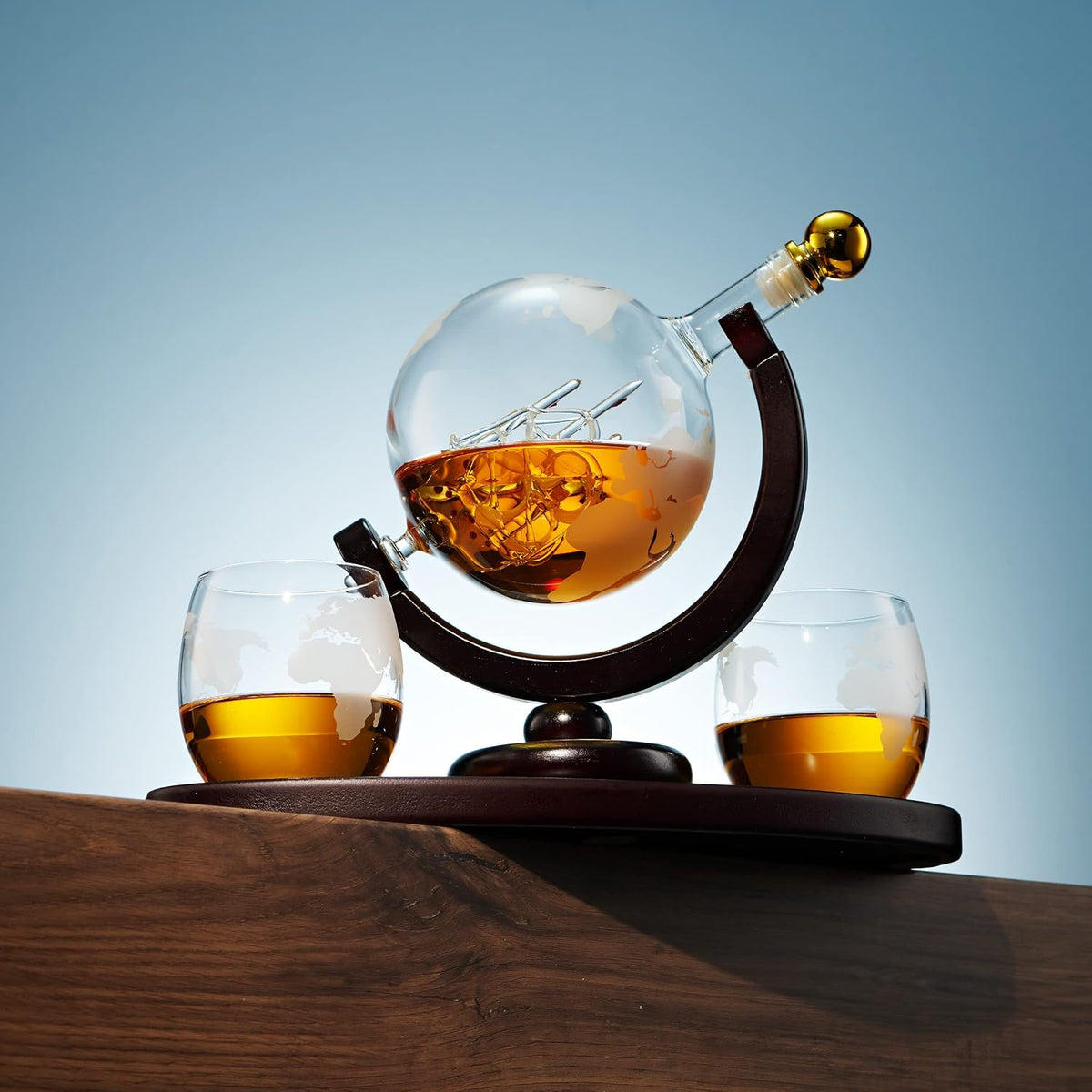 Godinger globe whiskey decanter set with two glasses on a wood table against a blue background