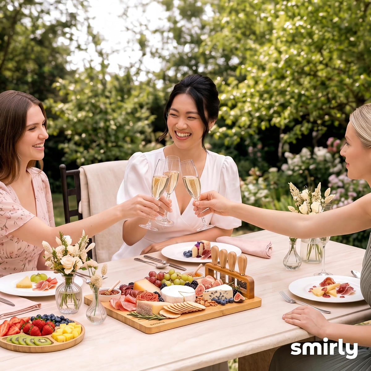 Friends toasting at an outdoor table with the SMIRLY charcuterie board