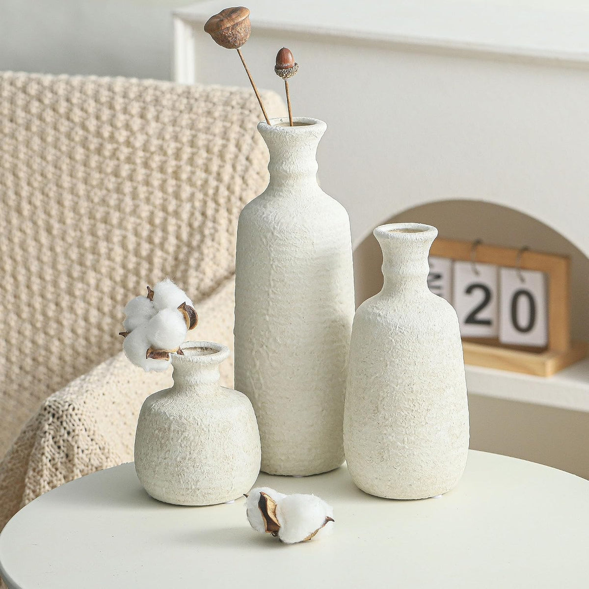 Three white ceramic vases on a round side table