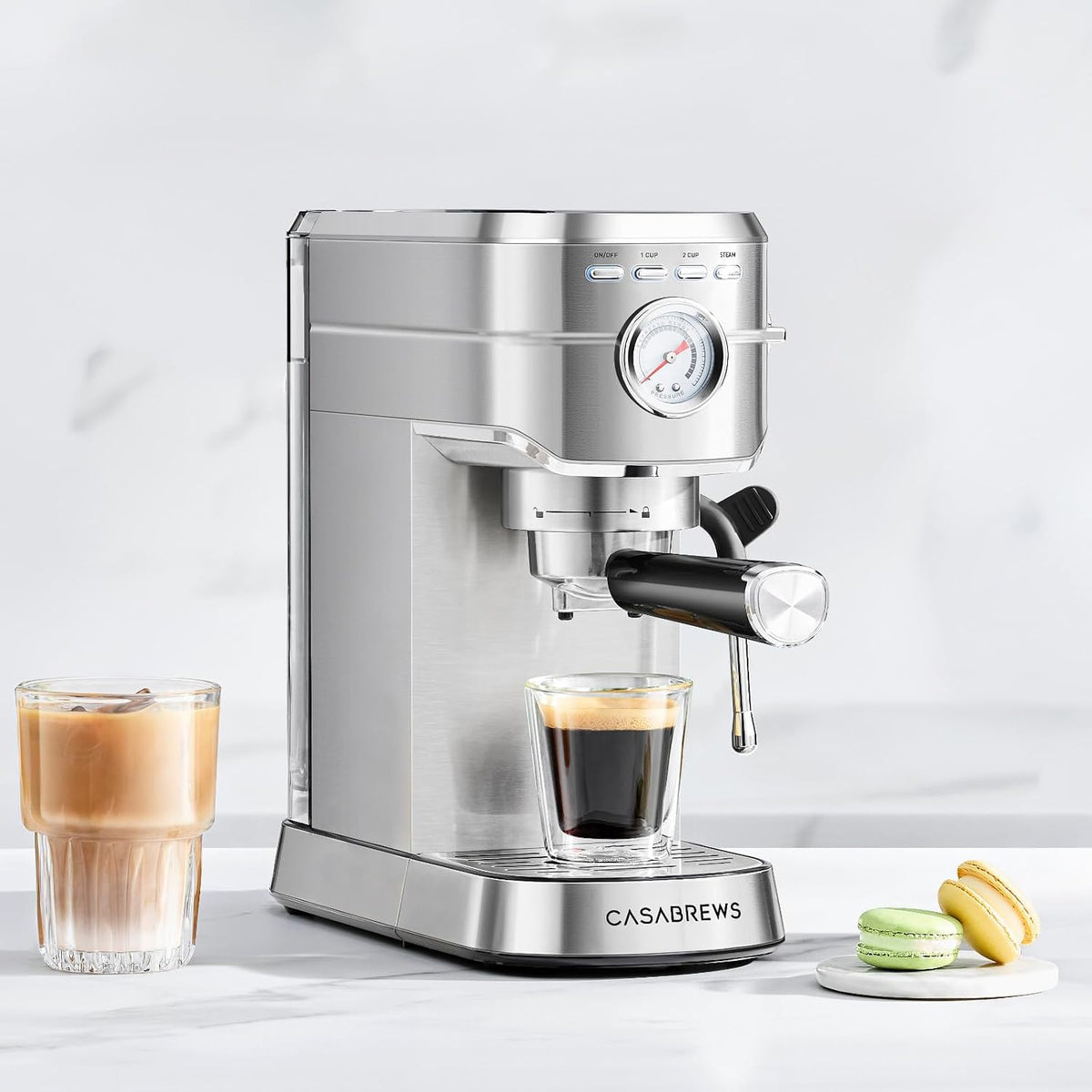 Espresso machine on a counter with a fresh espresso, an iced latte and macarons