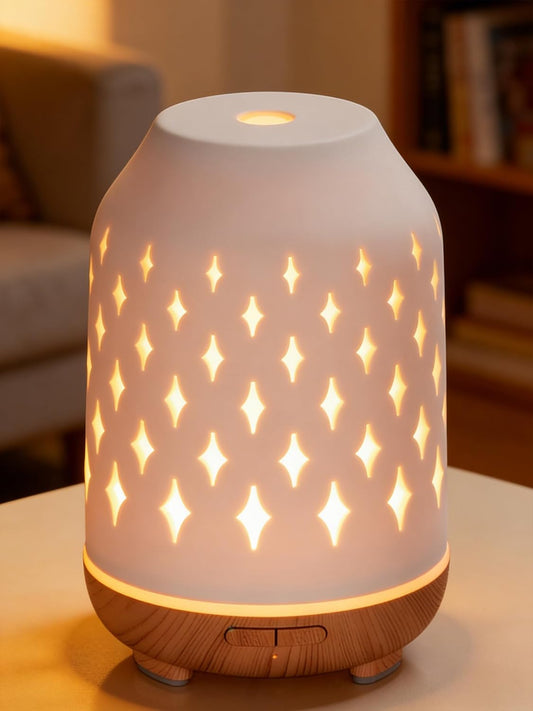 White ceramic diffuser lit from inside, its star cut-outs glowing on a side table