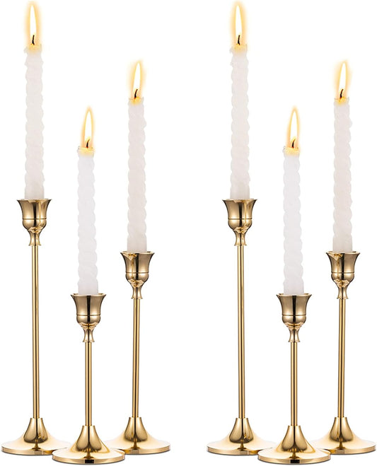 Six gold taper candle holders in three heights with white candles