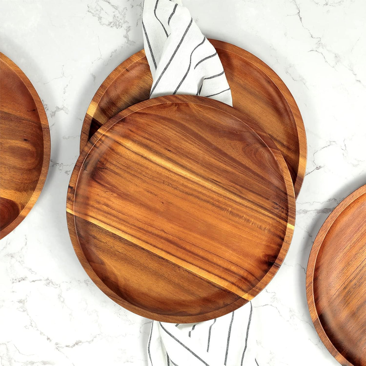 Acacia wood plates on a marble table with a striped napkin