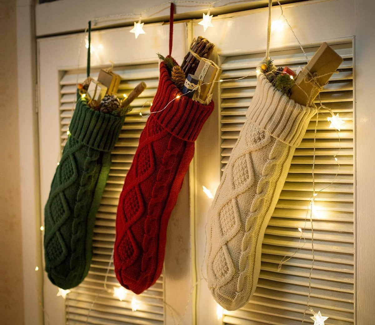 Knit stockings filled with gifts, hanging with string lights