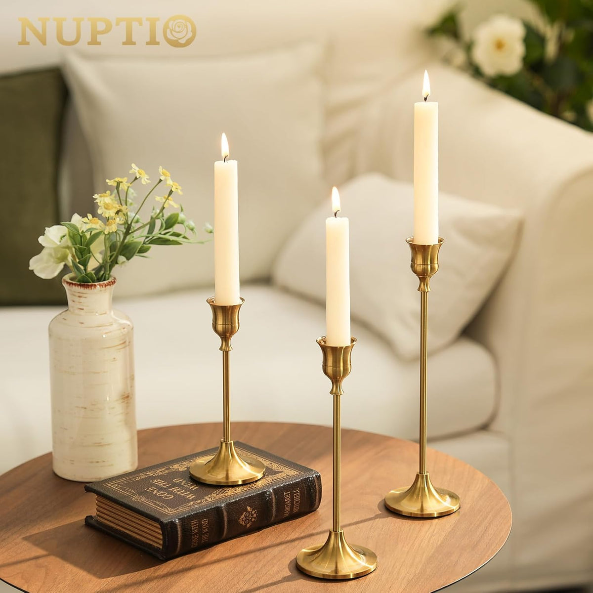 Three gold candle holders with candles on a side table