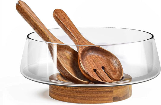 Glass salad bowl on an acacia wood base with a wooden fork and spoon