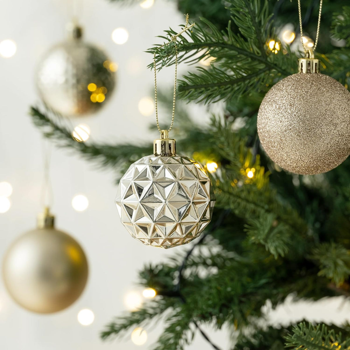 Champagne ornaments in three finishes hanging on a tree