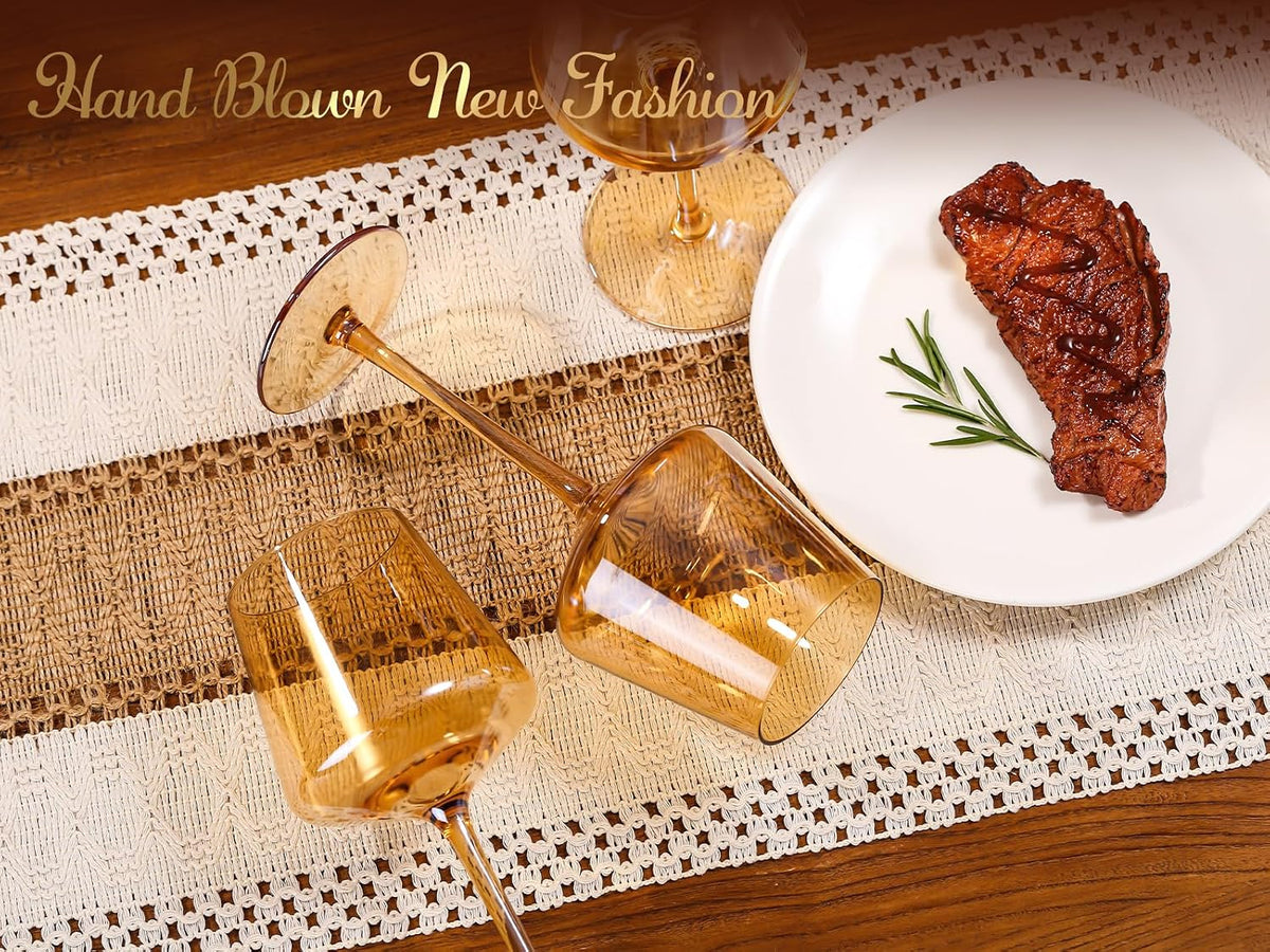 Amber wine glasses lying on a woven table runner next to a plate