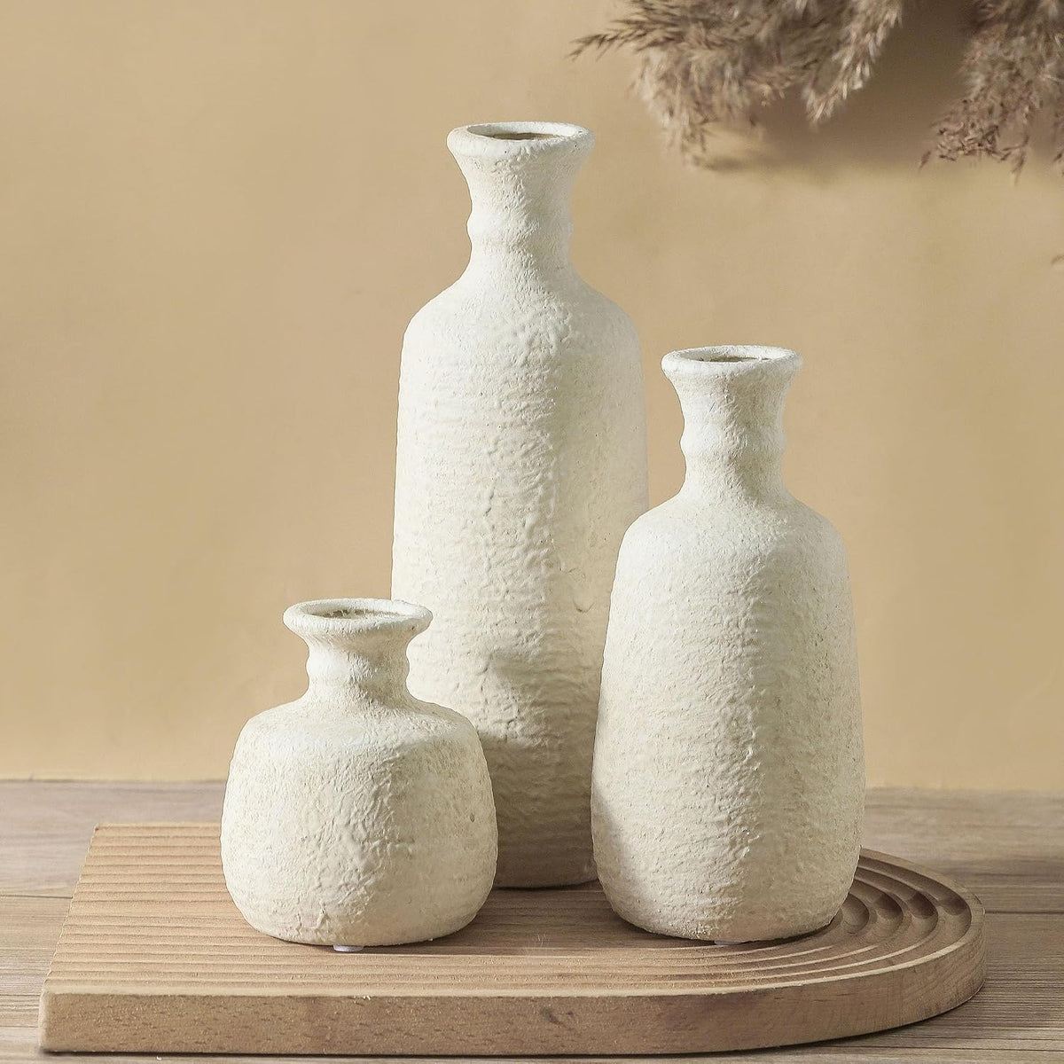 Three white ceramic vases on a wooden board