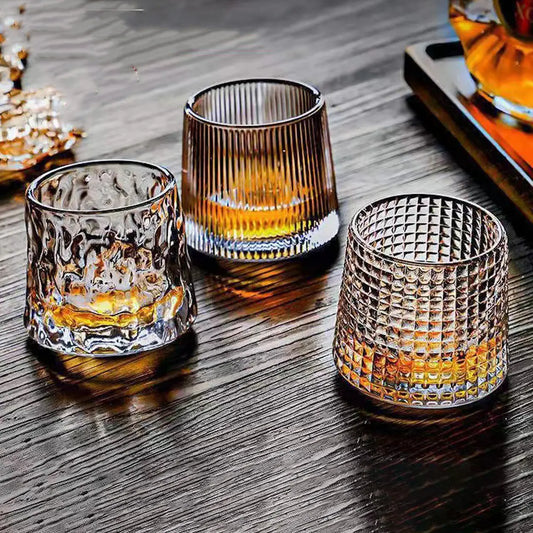 Set of 3 rotating whiskey glasses showing vertical, ice, and diamond styles on a wooden bar table