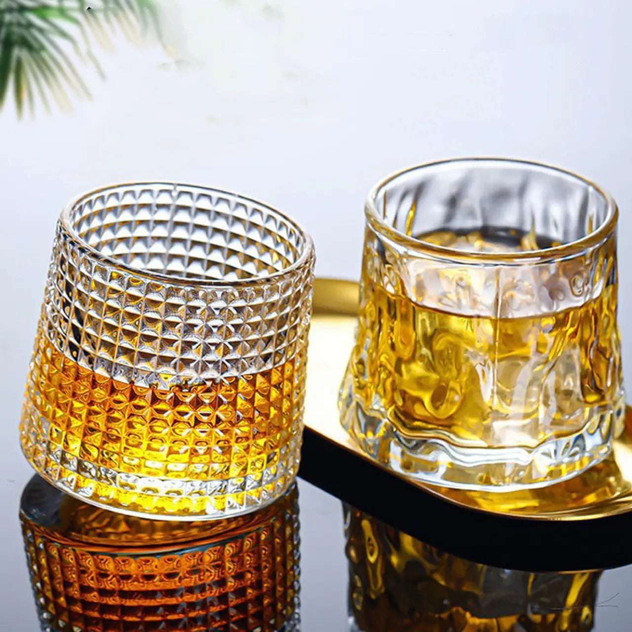 Rotating whiskey tumblers filled with bourbon and ice, perfect for home bars